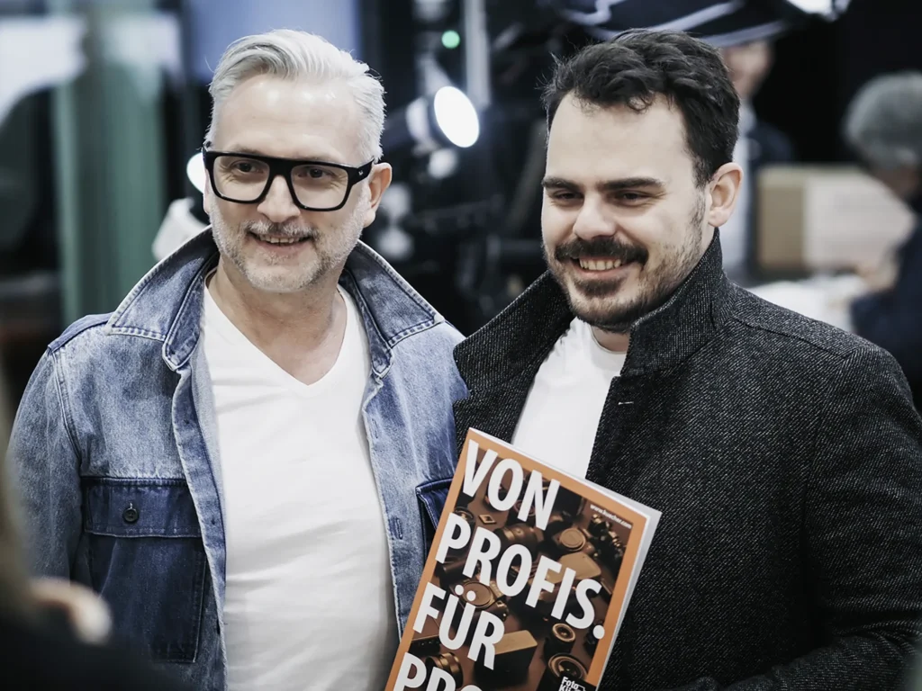 Michael Preschl, Werbefotograf und Visual Brand Specialist aus Salzburg, im Gespräch mit Teilnehmern einer Fachveranstaltung der Salzburger Berufsfotografie. Der Austausch konzentriert sich auf aktuelle Entwicklungen in der professionellen Fotografie und visuellen Kommunikation.