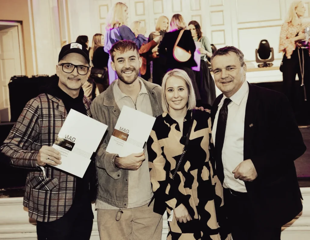 Michael Preschl, Werbefotograf und Visual Brand Specialist aus Salzburg, nimmt bei einer feierlichen Preisverleihung die Auszeichnung für den ersten Platz in der Kategorie Werbefotografie entgegen und präsentiert die Gewinnerurkunde auf der Bühne.