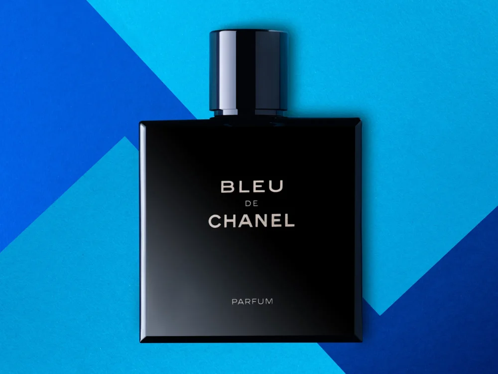 Bleu. De. Chanel. — Product Photography by Michael Preschl Bleu de Chanel Parfum in schwarzem quadratischem Hochglanzflacon mit zylindrischem Verschluss, platziert auf einem geometrisch aufgeteilten Hintergrund in drei Blautönen – Produktfotografie, Fotograf Michael Preschl